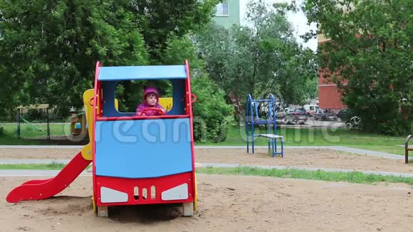 快乐的小女孩坐在操场上的彩色木车上视频的预览图