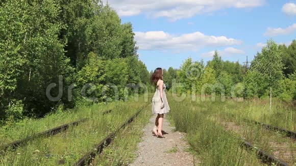 穿着裙子在铁路上跳舞的漂亮微笑女孩视频的预览图