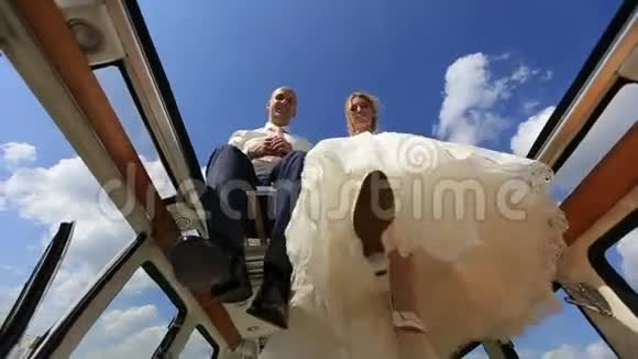 快乐的年轻快乐的新婚夫妇在复古的公共汽车顶上挥舞着双腿下面的视图视频的预览图