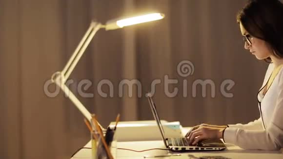 戴眼镜的女人在夜间办公室打手提电脑视频的预览图