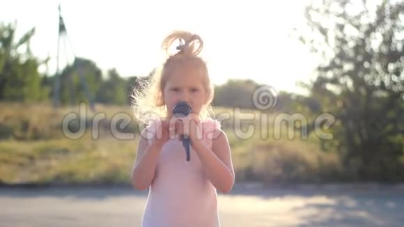 童女在夏日夕阳的余晖中对着麦克风唱着一首歌有才华的孩子是一个音乐声音视频的预览图