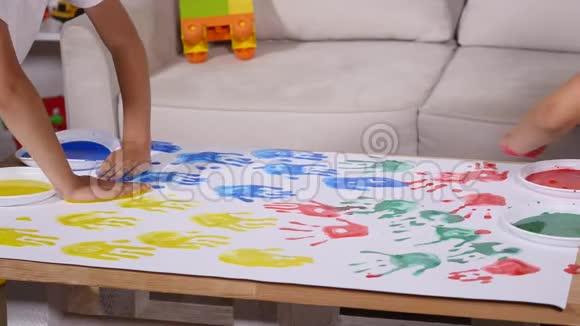 一个小可爱快乐有趣的孩子在白纸上画彩色手印视频的预览图
