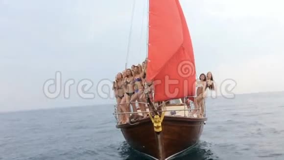一群穿着比基尼的苗条模特在豪华游艇上放松在公海上扬起红帆视频的预览图