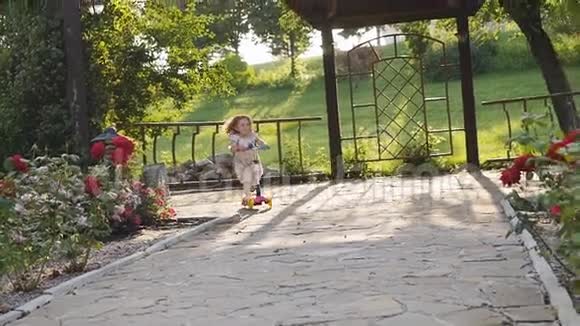 夏天公园里可爱的卷发小女孩骑摩托车视频的预览图