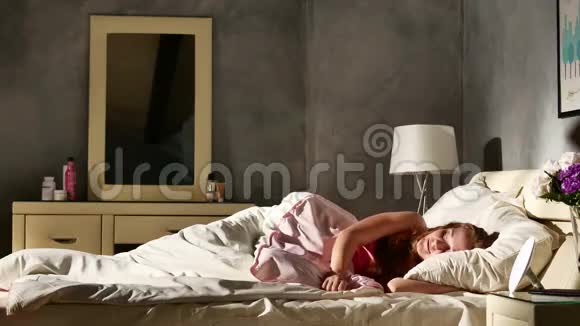 年轻快乐的女人从卧室的床上醒来然后回去睡觉视频的预览图