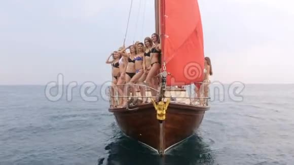 一群穿着比基尼的苗条模特在豪华游艇上放松在公海上扬起红帆视频的预览图
