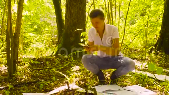 女生态学家在森林里拍摄植物视频的预览图