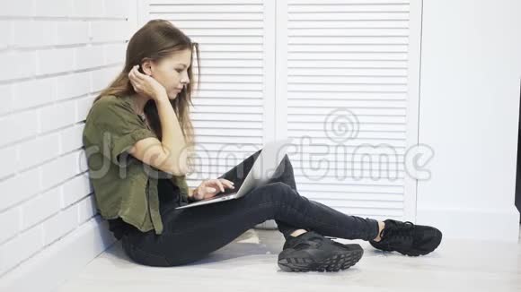 年轻女子在地板上用笔记本电脑打字视频的预览图