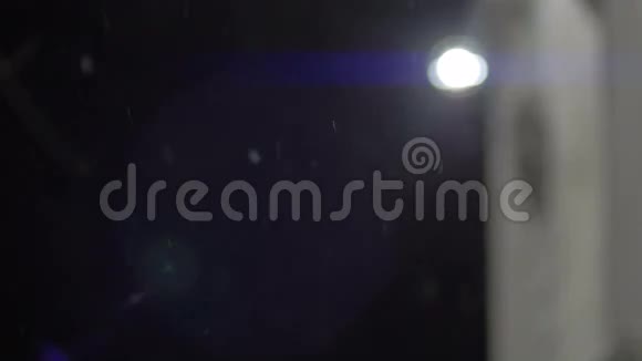 在模糊的光线背景下雪花飘落的夜景视频的预览图