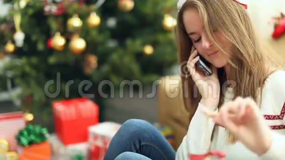 戴着圣诞帽的漂亮女孩在电话里说话视频的预览图