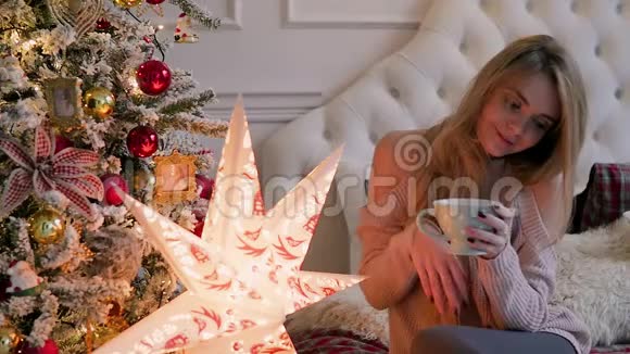 年轻女子坐在圣诞节的内部茶杯享受假期吧视频的预览图