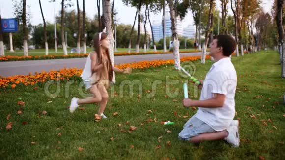 爸爸和女孩在草坪上吹肥皂泡视频的预览图