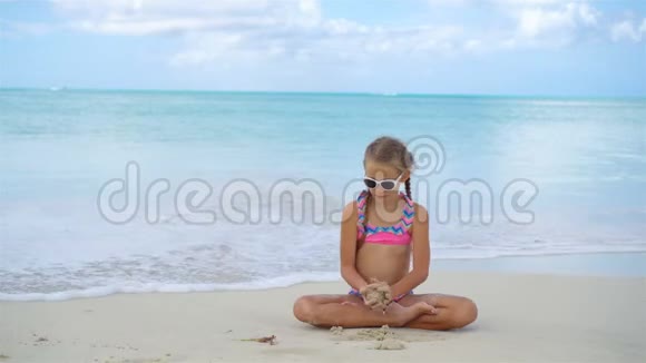 可爱活泼的小女孩坐在沙滩上视频的预览图