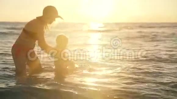 幸福的家庭在海里游泳母亲和孩子在海水中从城市里玩一个有趣的休息家庭幸福视频的预览图