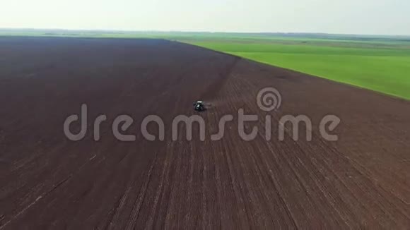 鸟瞰田野拖拉机在春天犁地拉开距离变焦视频的预览图