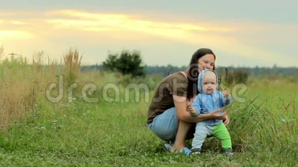 快乐的家庭和婴儿在球场上玩耍日落前美丽的橙色天空微笑和欢乐视频的预览图