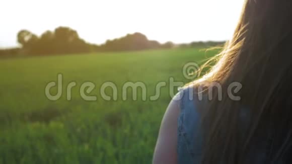 美丽的年轻姑娘长着一头直发迎风而立夕阳西下站在田野里视频的预览图