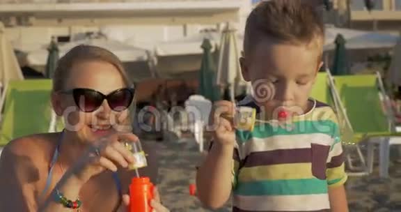 母亲和儿子在海滩上吹泡泡视频的预览图