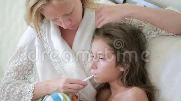 母亲对待生病的孩子妈妈帮助一个小女孩康复温度计视频的预览图