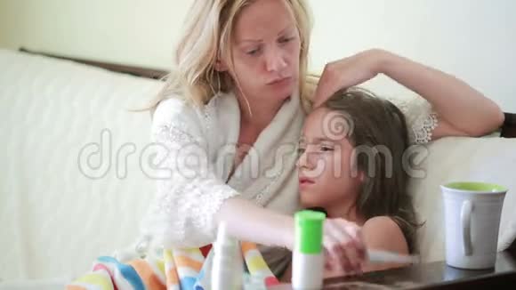 母亲对待生病的孩子妈妈帮助一个小女孩康复温度计视频的预览图
