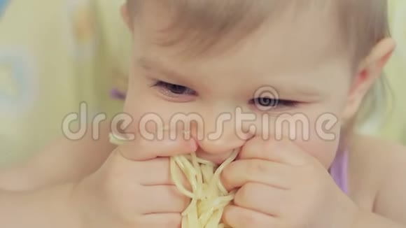 可爱的小女孩用她的手指吃意大利面并享受它视频的预览图