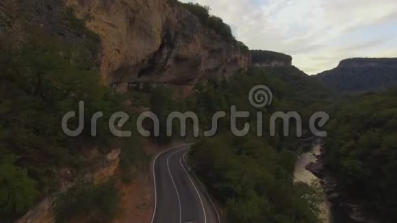 在一条乡村景观道路上飞行跟随一辆车行驶在上面上面有郁郁葱葱的绿叶农田空中射击视频的预览图