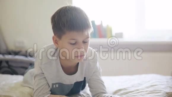 年轻的十几岁的男孩在床上看数字平板电脑视频的预览图