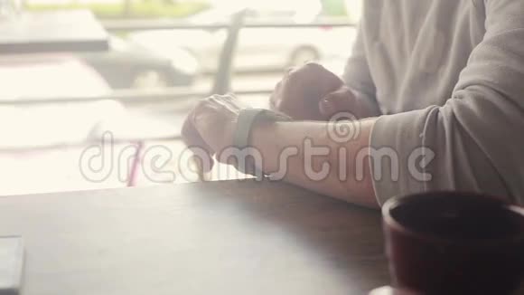 有智能手表的人坐在城市的咖啡馆里视频的预览图