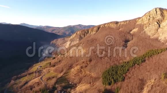 空中拍摄秋天的树林在山上用橙色的干叶太阳在天空的高处用无人机拍摄4K视频的预览图