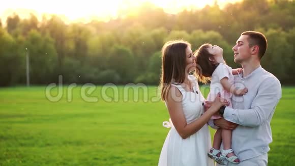 快乐的年轻家庭带着孩子在夏天的田野上散步健康的母亲父亲和小女儿享受大自然视频的预览图