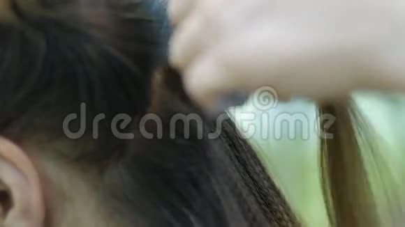 理发师在发廊里用矫直机对漂亮的女人的头发卷曲的波纹视频的预览图