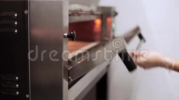 厨师在商业厨房的烤箱里放一个生披萨视频的预览图