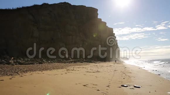 英国西湾侏罗纪海岸多塞特阳光照耀着砂岩峭壁远处的人在沙滩上浪迹天涯视频的预览图