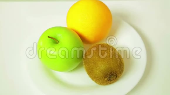 白色盘子上的橙色猕猴桃和绿色苹果旋转成一个圆圈视频的预览图