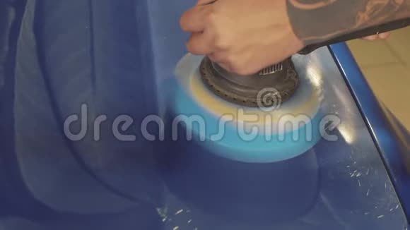 师傅在一个汽车车间里用抹油机打磨深蓝色跑车视频的预览图
