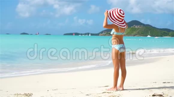 可爱的小女孩戴着大帽子走在沙滩上视频的预览图