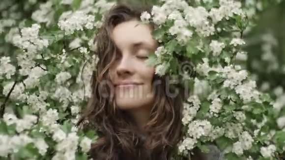 年轻幸福的笑着绿眼睛的女人带着鲜花看着相机自然美视频的预览图