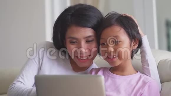 母亲和女儿在沙发上用笔记本电脑视频的预览图