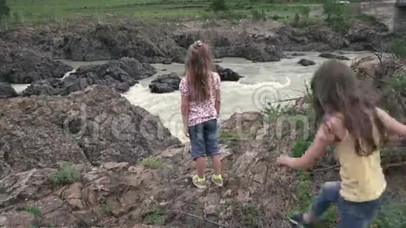 小女朋友在靠近一条山河的岩石上欣赏令人叹为观止的景色女孩旅行者手牵手视频的预览图