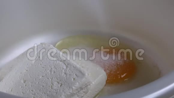 奶酪蛋糕的准备加糖容器里放着干酪一个鸡蛋被打掉了视频的预览图