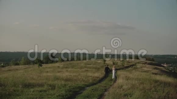 一对恋人在夕阳的田野里一对恋人手牵着手走来走去视频的预览图