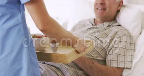护士为老人提供托盘和早餐视频的预览图