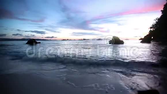 海滩上的日落宁静的田园诗般的景色金色的日落在海面上海浪慢慢地溅在沙滩上视频的预览图