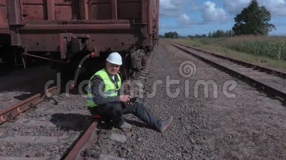 铁路工人与平板电脑坐在铁路附近的货车视频的预览图