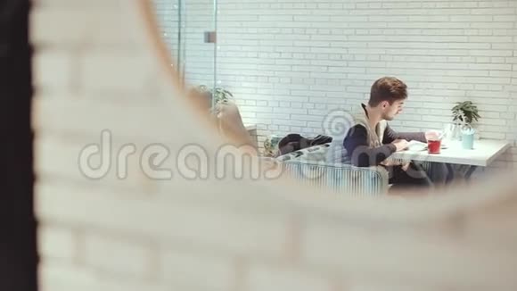 有智能手机的年轻人坐在镜子里的咖啡馆里视频的预览图
