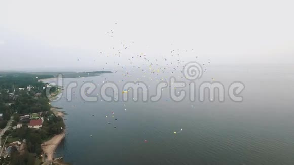 鸟瞰许多五颜六色的气球飞上天空在海岸海滩上视频的预览图