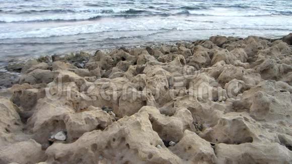 平静的海浪冲刷着石灰石海滩的特写视频的预览图