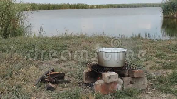 在河岸的木桩上煮鱼汤视频的预览图
