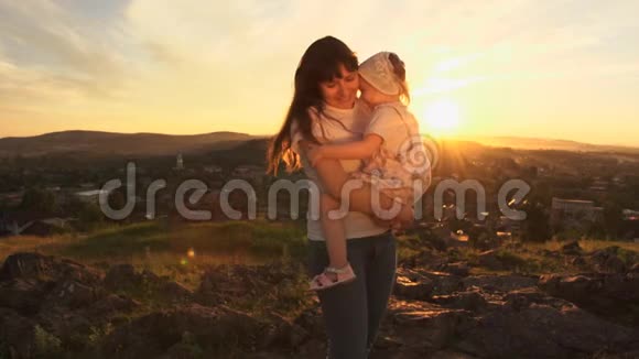 一个幸福的家庭在日落时母亲抱着她的女儿在怀里视频的预览图