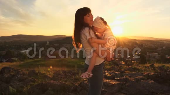 一个幸福的家庭在日落时母亲抱着她的女儿在怀里视频的预览图